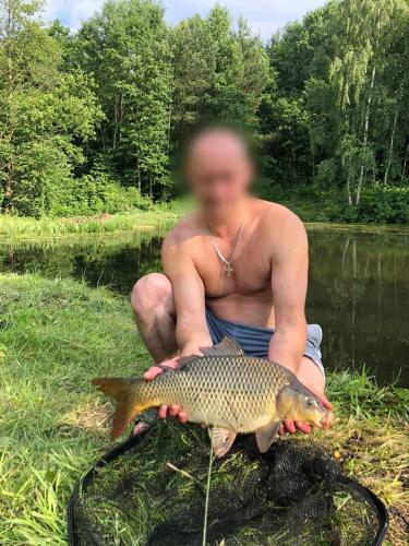 a man holding a fish in front of a river at Будинки рибалки in Sudovaya Vishnya