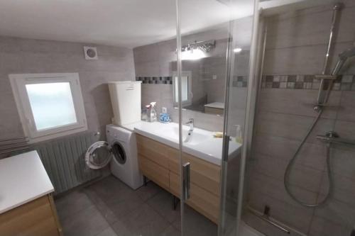 une salle de bain avec douche et lavabo et une machine à laver dans l'établissement Maison de village dans un mas, à Aumelas