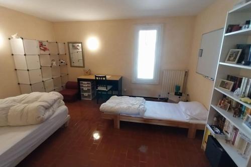 une chambre avec deux lits et un bureau et une fenêtre dans l'établissement Maison de village dans un mas, à Aumelas