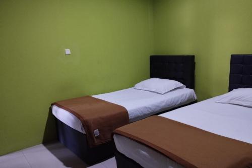 two beds in a room with green walls at OYO 93764 Homestay Citra in Kendari