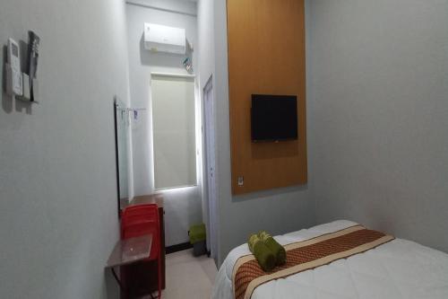 ein Schlafzimmer mit einem Bett und einem TV an der Wand in der Unterkunft OYO 93769 Setia Budi Guest House 2 in Sragen