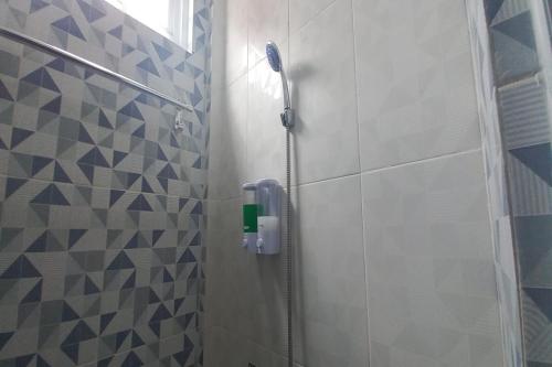eine Dusche im Bad mit blauen und weißen Fliesen in der Unterkunft OYO 93769 Setia Budi Guest House 2 in Sragen