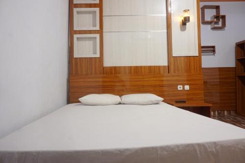 Una cama blanca con dos almohadas encima. en OYO 93770 Pondom Danu 77, en Kendari
