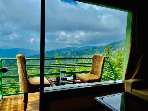 two chairs and a table on a balcony with a view at Aachman Nature Valley Resort Shimla in Shimla