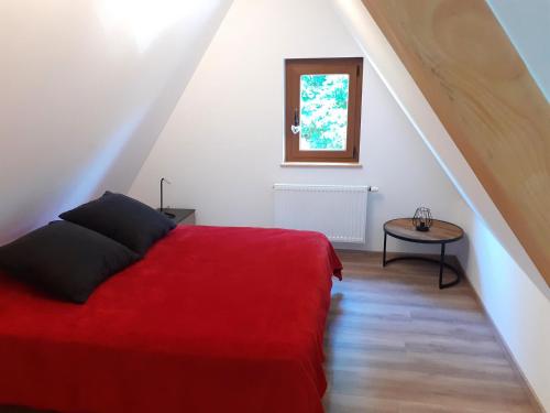 1 dormitorio con cama roja y mesa pequeña en Gîte de la Muse, en Rouffach