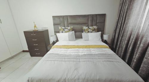 a bedroom with a large bed and a dresser at Bryanston Guest Cottage in Johannesburg