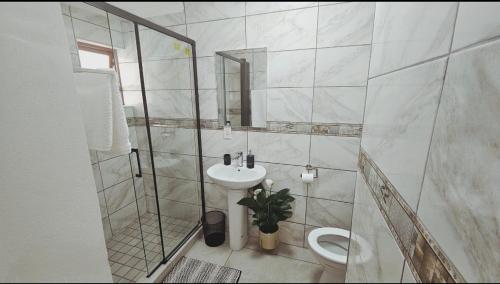 une salle de bain blanche avec un lavabo et des toilettes dans l'établissement Bryanston Guest Cottage, à Johannesbourg