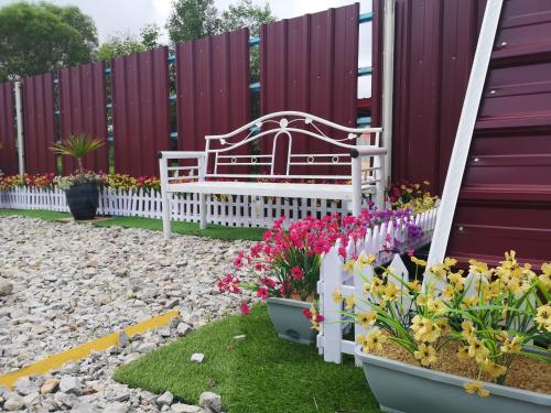 eine Bank in einem Garten mit Blumen und einem Zaun in der Unterkunft Red Triangle Cottage Roomstay in Kampong Kemaman