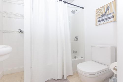 a white bathroom with a toilet and a shower curtain at 1-BDRM Apartment with Balcony - Heart of Downtown and Wynwood in Miami