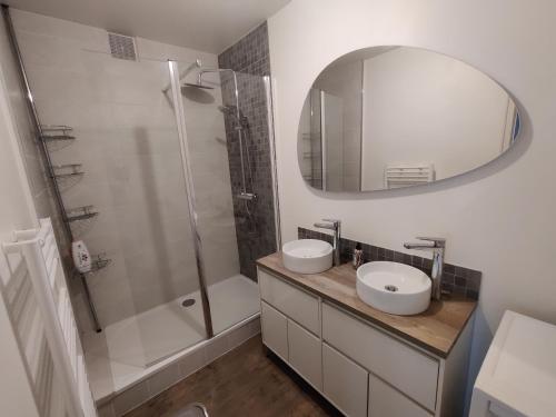 La salle de bains est pourvue de 2 lavabos, d'une douche et d'un miroir. dans l'établissement Appartement 2 Chambres INDIaNA Hyper centre, à Vitré