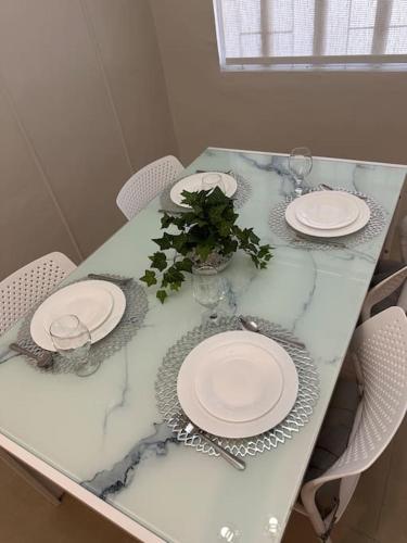 a table with plates and glasses and a plant on it at Japandi Home C - Fully Aircon, WIFI, Hot shower, 24hGuard, Center, near Malls in General Santos
