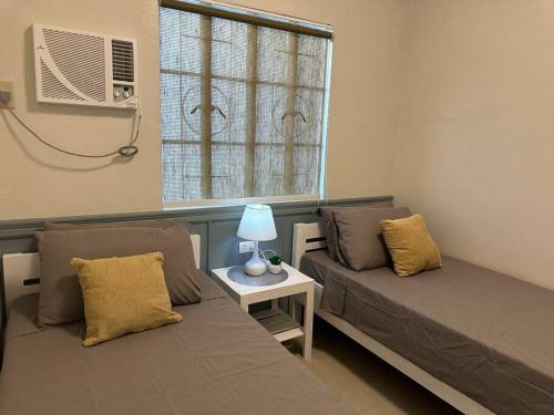 sala de estar con 2 camas y ventana en Japandi Home C - Fully Aircon, WIFI, Hot shower, 24hGuard, Center, near Malls en General Santos