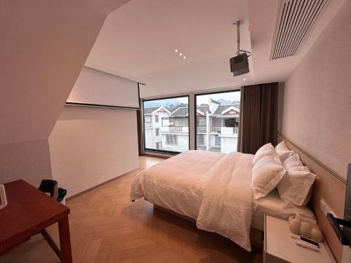 - une chambre avec un grand lit et une grande fenêtre dans l'établissement Flower Whisperer Homestay, à Zhangjiajie