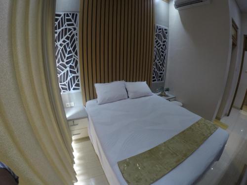 una camera da letto con un letto con lenzuola bianche e una finestra di Capital O 93718 Homestay 3 Bidadari a Yogyakarta