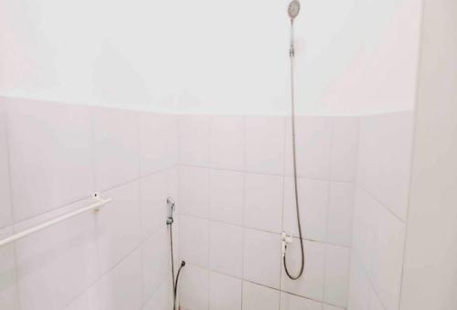 a shower in a white tiled bathroom at OYO 93722 Shannhay Guest House in Jakarta