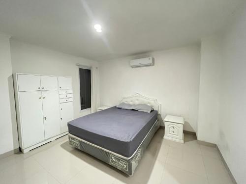 um quarto com uma cama num quarto branco em OYO 93721 RuPA Near Jakarta Velodrome em Jakarta