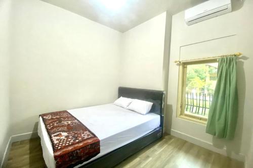 a small bedroom with a bed and a window at SPOT ON 93717 Nayus Homestay Syariah 4 in Yogyakarta