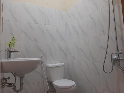a white bathroom with a toilet and a sink at Capital O 93719 Homestay Omah Bidadari in Prambanan
