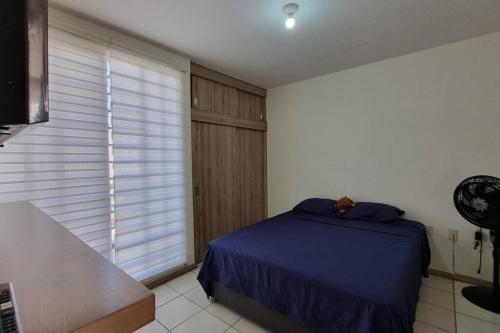 1 dormitorio con cama azul y ventana grande en Excelente lugar para descansar, en Emiliano Zapata