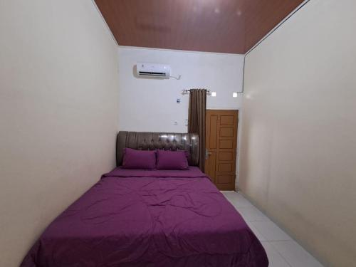 a bedroom with a purple bed in a white room at OYO 93714 Guest House Gembul Syariah in Jambi
