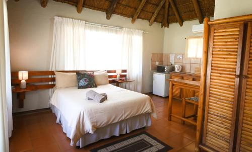 a bedroom with a bed with a window and a kitchen at Northgate Lodge in Louis Trichardt
