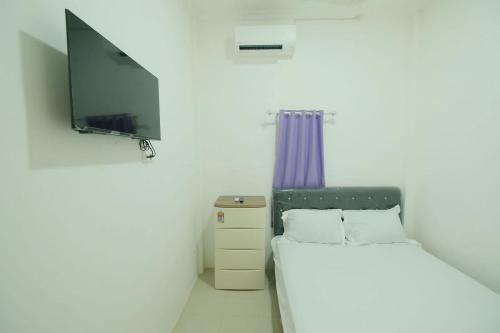 a bedroom with a bed and a flat screen tv at OYO 93756 Qq Kost in Laleng-balandae