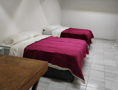 Habitación con 2 camas y mesa de madera. en La Cortesana en Ciudad de México