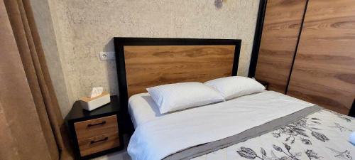 een slaapkamer met een bed met een houten hoofdeinde bij Apartment Rustaveli 118 in Koetaisi