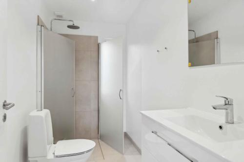 a white bathroom with a toilet and a sink at Brand New And Modern Summer House In Kulhuse in Jægerspris