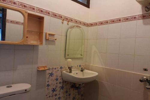 een witte badkamer met een wastafel en een spiegel bij OYO 93706 Penginapan Syariah Hj. Kenan in Bukittinggi