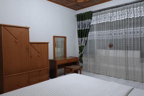 een slaapkamer met een bed, een dressoir en een spiegel bij OYO 93706 Penginapan Syariah Hj. Kenan in Bukittinggi