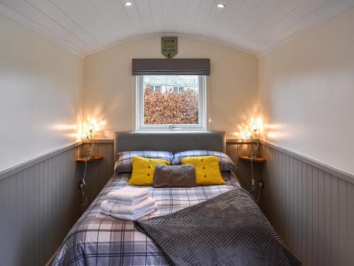 Un dormitorio con una cama con almohadas amarillas y una ventana en Greengill Farm Shepherds Hut- Ukc3632 en Gilcrux