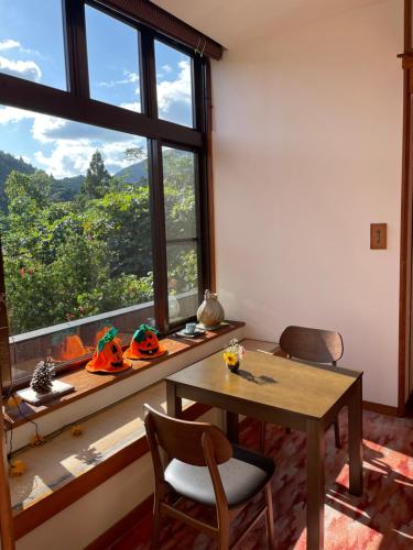 um quarto com uma mesa e cadeiras e uma grande janela em Yunominesou em Hongu