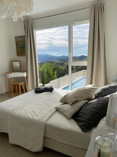 une chambre avec un grand lit et une grande fenêtre dans l'établissement Villa Phi, à Oletta