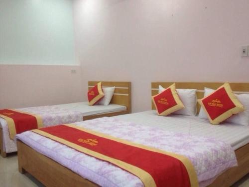 una camera con due letti con cuscini rossi e gialli di Kim Ngân Hotel Lào Cai a Lao Cai