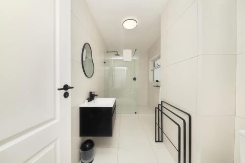 ein weißes Badezimmer mit einem Waschbecken und einem Spiegel in der Unterkunft Mountain facing 2 bedroom apartment in Kapstadt