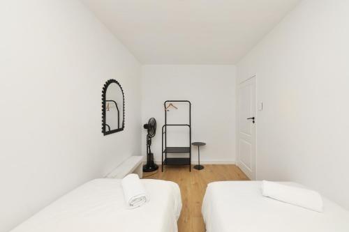 ein weißes Zimmer mit 2 Betten und einem Spiegel in der Unterkunft Mountain facing 2 bedroom apartment in Kapstadt