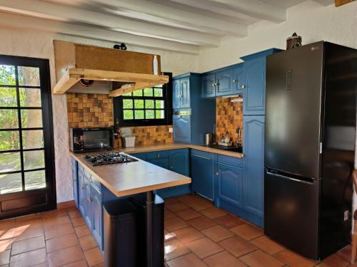 eine Küche mit blauen Schränken und einem schwarzen Kühlschrank in der Unterkunft Villa Yéyéyette spacieuse 6 à 8 personnes in Andernos-les-Bains