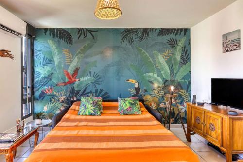 a bedroom with a bed with a tropical wallpaper at Ti case a moin - Joli T2 en bord de mer in Saint-Pierre