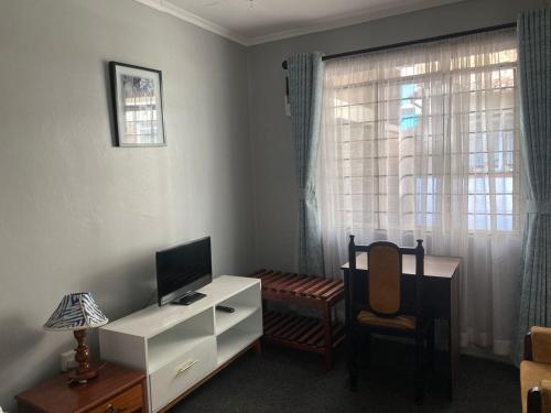 Camera con scrivania, TV e sedia. di Quaint one bedroom guest house near main airport a Nairobi