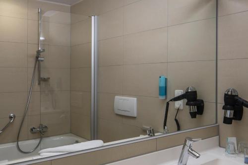 a bathroom with a shower and a sink and a bath tub at Austria Trend Hotel Europa Salzburg in Salzburg