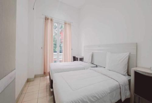 a white bedroom with two beds and a window at TOS Residence Near Gading Serpong in Kampung Sawah