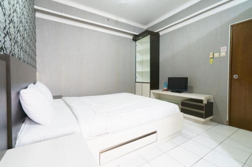 una camera con letto bianco e TV di Capital O 93760 Apartemen Gateway Cicadas By Jh Group a Bandung