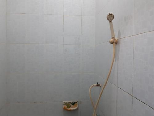a shower head in a white tiled bathroom at SPOT ON 93776 Intan Homestay in Nagoya