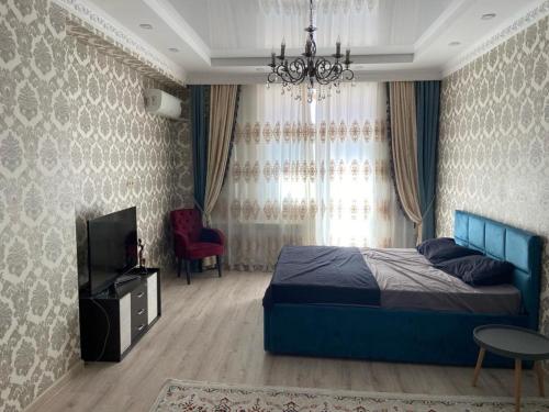 Schlafzimmer mit einem Bett, einem TV und einem Kronleuchter in der Unterkunft ЖК Green Plaza in Aqtau