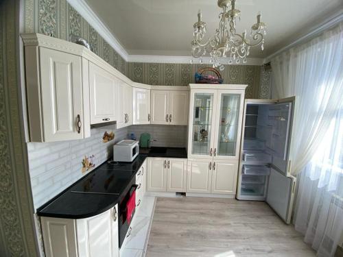 a kitchen with white cabinets and a chandelier at ЖК Green Plaza in Aktau