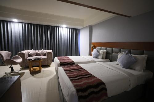 um quarto de hotel com duas camas e uma cadeira em Eastin Hotels em Hyderabad