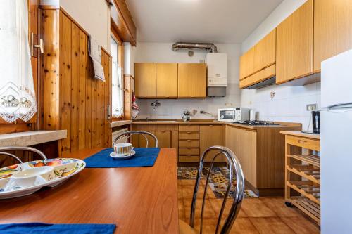 a kitchen with wooden cabinets and a wooden table with chairs at Vacanze Francesca in Bussolengo