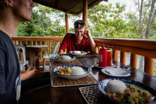 a woman sitting at a table with plates of food at Dave the Cave Eco Lodge and Cultural Campsite in Rubirizi