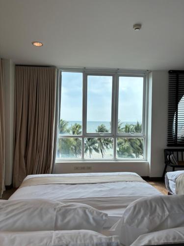 a bedroom with two beds and a large window at The Beach Bangsaen by Thanthita next to Wonnapa beach in Bangsaen